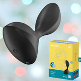 A sleek, curved electronic device sits on a colorful soft-focus background, complementing the vibrant yellow box labeled "Satisfyer Sweet Seal - Black" by Satisfyer. The accompanying illustration and product details highlight its design for an experience tailored to prostate massages and anal stimulation.